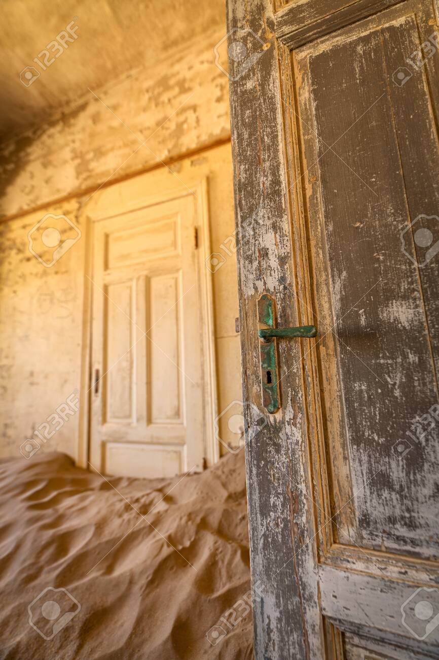 A close up vertical photograph of two old worn doors, with desert sand filling the abandoned room, taken in the ghost town of Kolmanskop, Namibia. - 142556591 A close up vertical photograph of two old worn doors, with desert sand filling the abandoned room, taken in the ghost town of Kolmanskop, Namibia. - 142556591