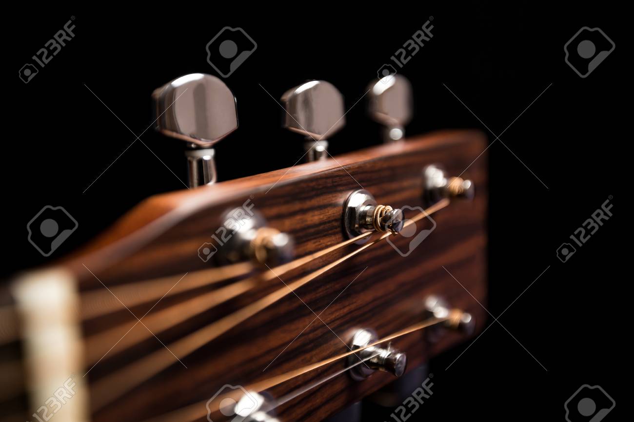 head of guitar on a black background with the strings nut and
