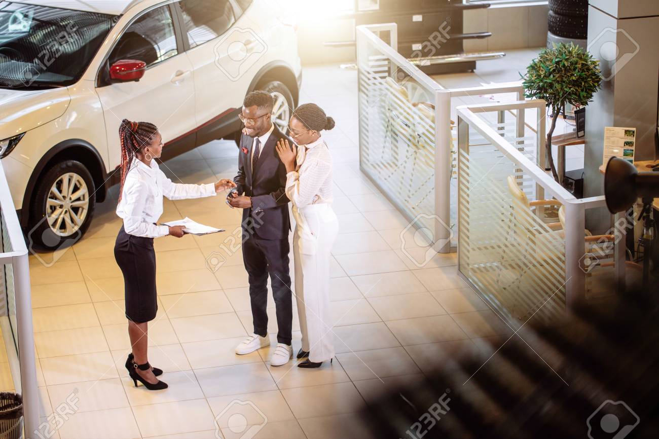 car salesman standing at dealership telling about features of car to customers - 94925656 car salesman standing at dealership telling about features of car to customers - 94925656