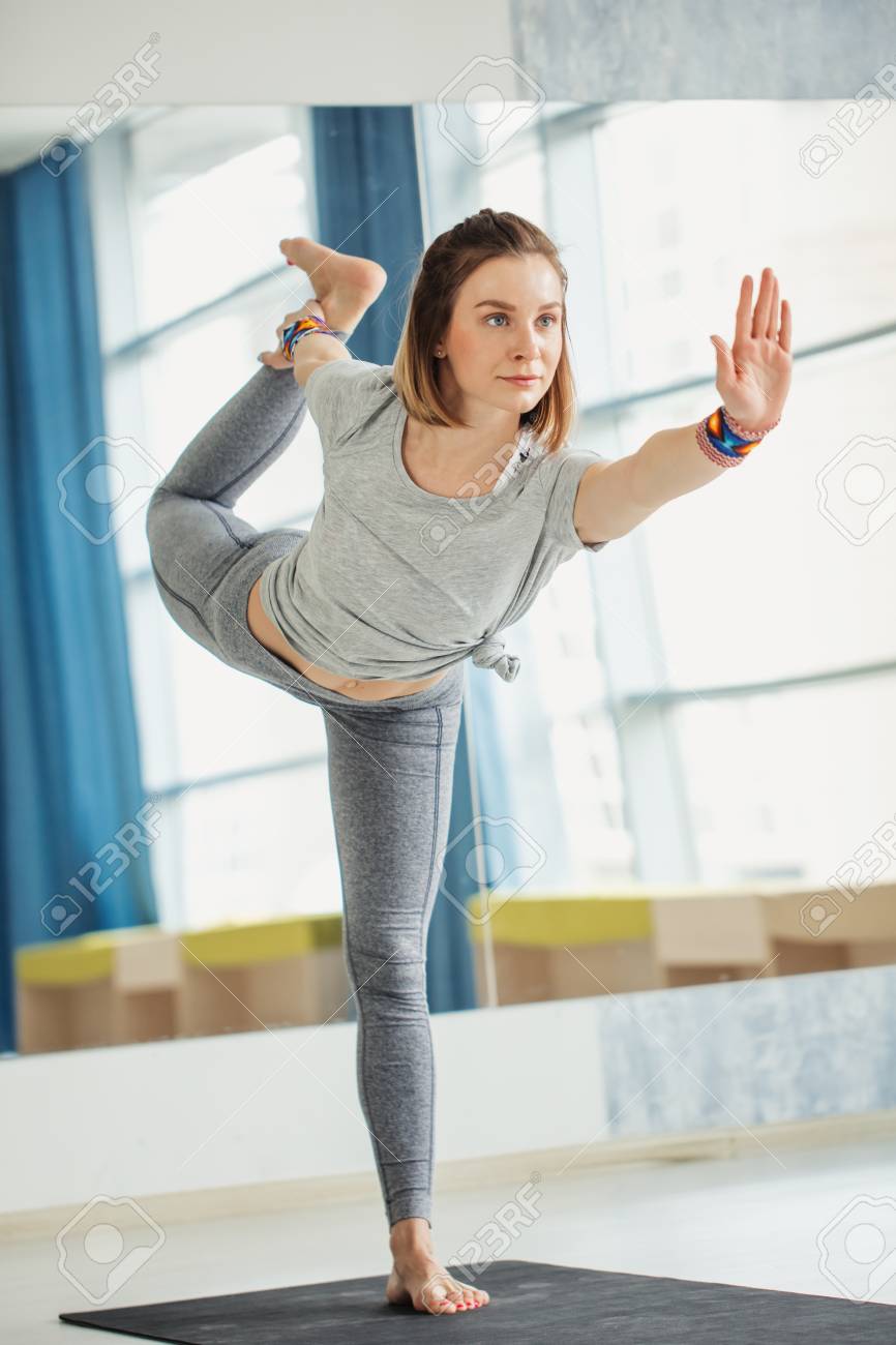 Young fit woman doing a yoga pose standing with one leg raised.. Young fit woman doing a yoga pose standing with one leg raised..