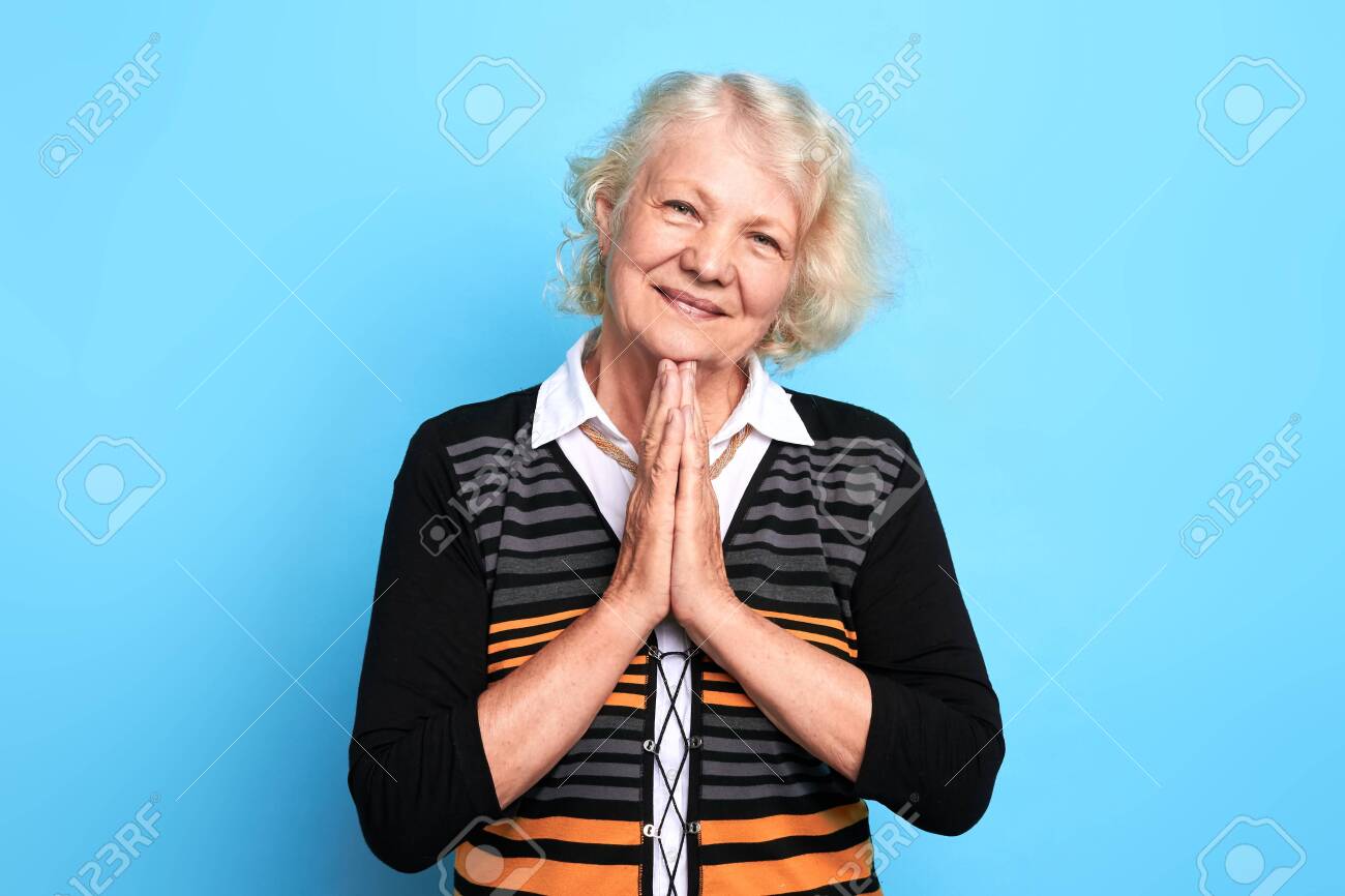 Senior happy blonde woman keeping palms together, praying the God. close up portrait. isolated blue background. strength of pray, kindness, body language, wish. - 127369640 Senior happy blonde woman keeping palms together, praying the God. close up portrait. isolated blue background. strength of pray, kindness, body language, wish. - 127369640