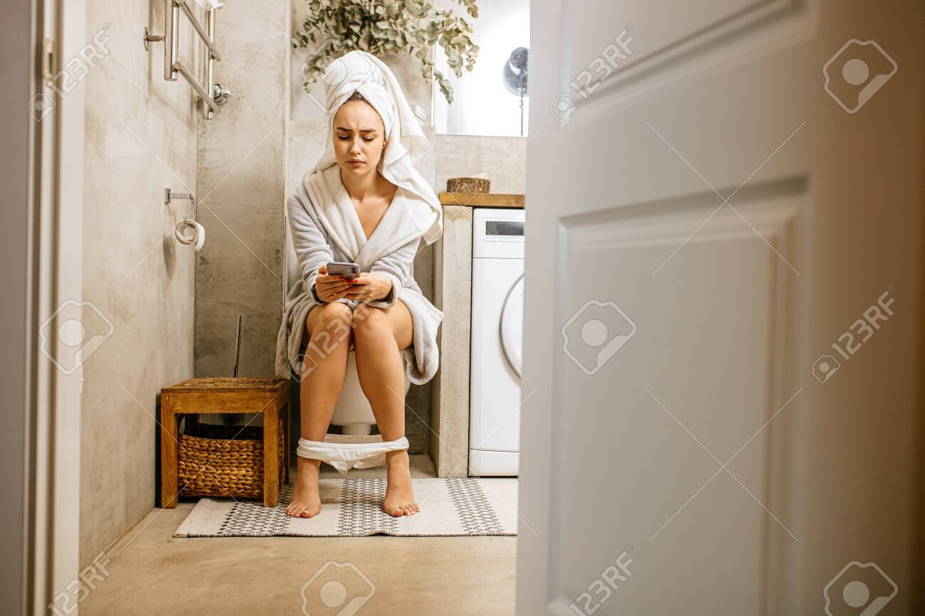 女放尿 若い白人女性は便器の上に座り、朝はバスローブとタオルを着て放尿する女性です。トイレでスマートフォンを持つ美しい女性。便秘、下痢、胃痛の概念の写真素材・画像素材  Image 145563540