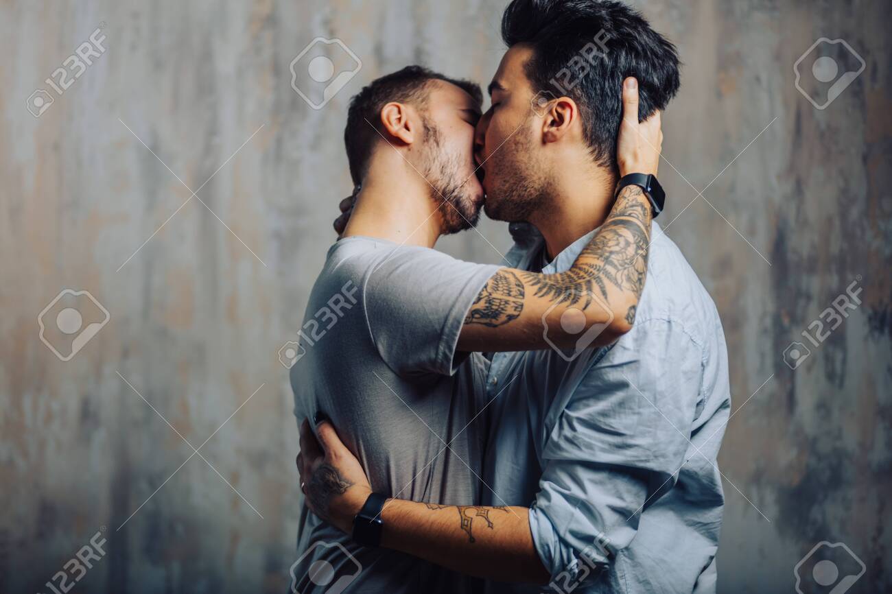 Mixed Race Couple Of Gay Male Sexual Interactions, Asian And Caucasian Men  Cuddling And Kissing Each Other Against Grey Loft Background Stock Photo,  Picture and Royalty Free Image. Image 152453189.
