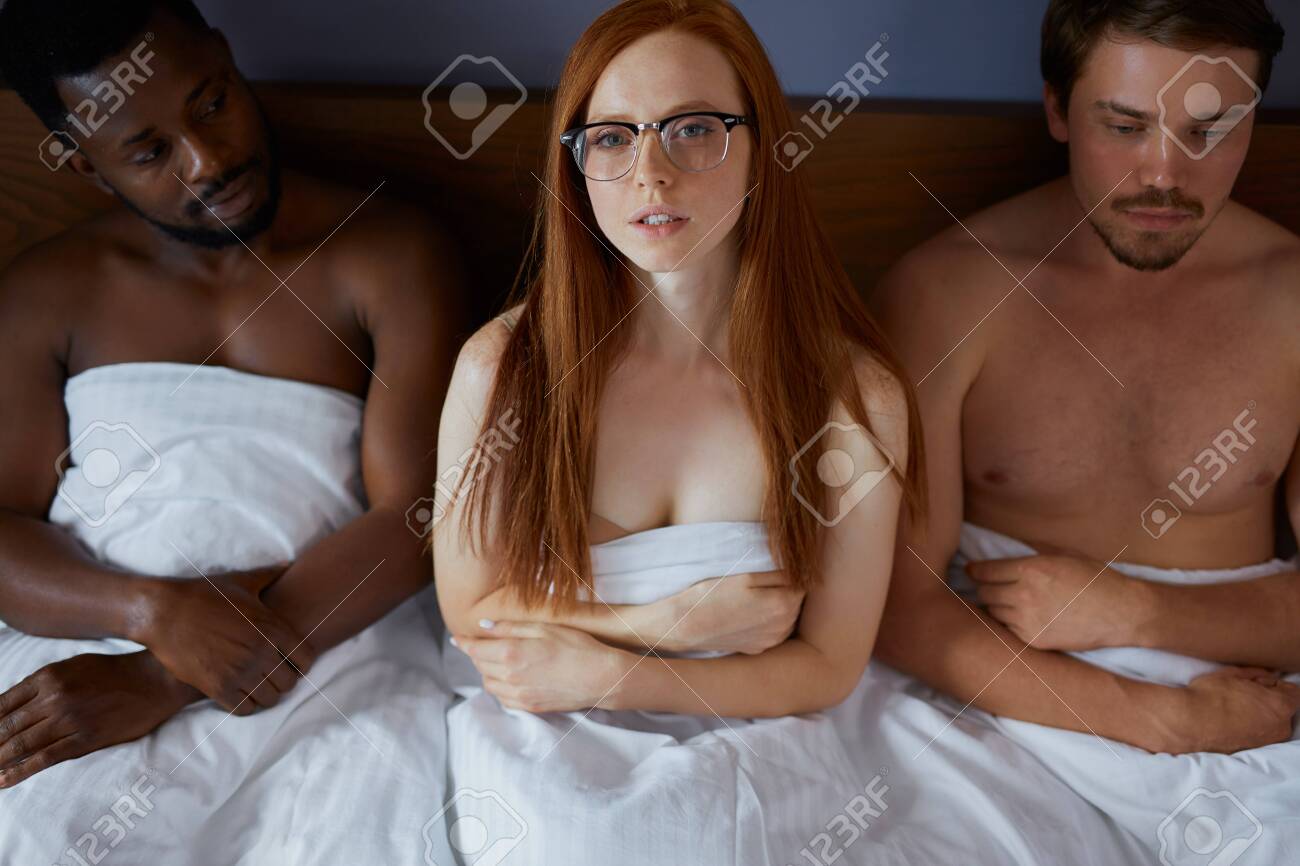 sex　白人 アフリカと白人の男性は赤毛のセクシーな女性と一緒にベッドに横たわっています、彼らは彼女とセックスしたいのですが、彼らはそれを得ることができません、彼女は熟考していますの写真素材・画像素材  Image 154367174