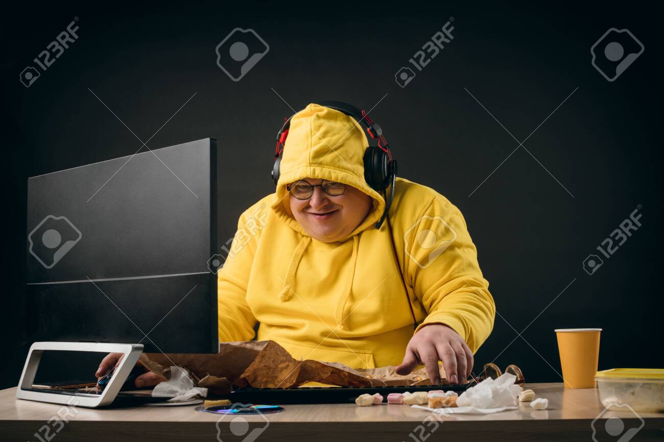 Funny Guy In Yellow Hoody Getting Pleasure From Online Games. Close Up  Photo. Isolated Black Background.studio Shot. Computer Hacker Making Up A  New Programme.crime Concept Stock Photo, Picture and Royalty Free Image., image size:1300x866