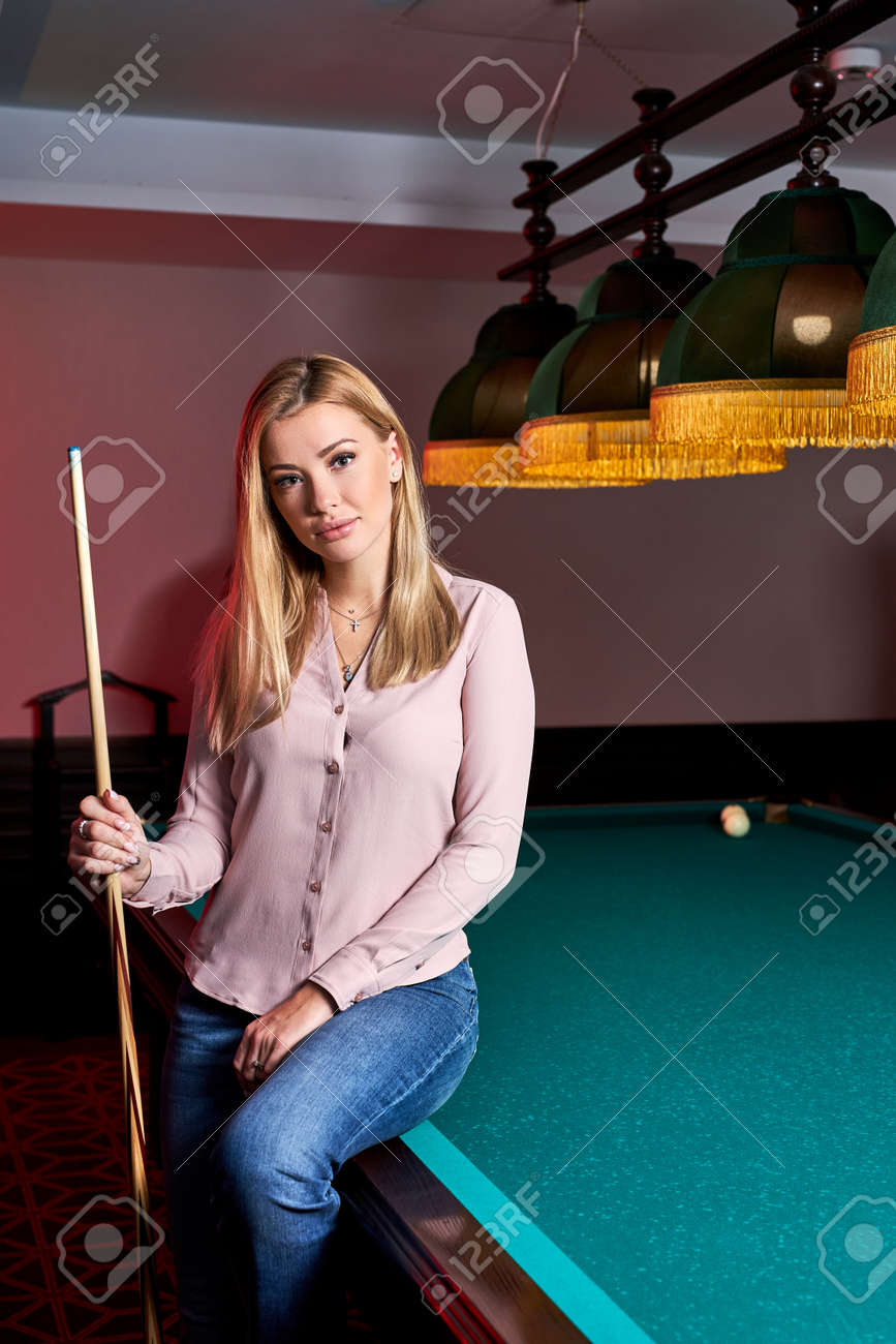 blond female came to spend pleasant time playing snooker, she is posing at camera, sitting on pool, billiards table - 169212536 blond female came to spend pleasant time playing snooker, she is posing at camera, sitting on pool, billiards table - 169212536