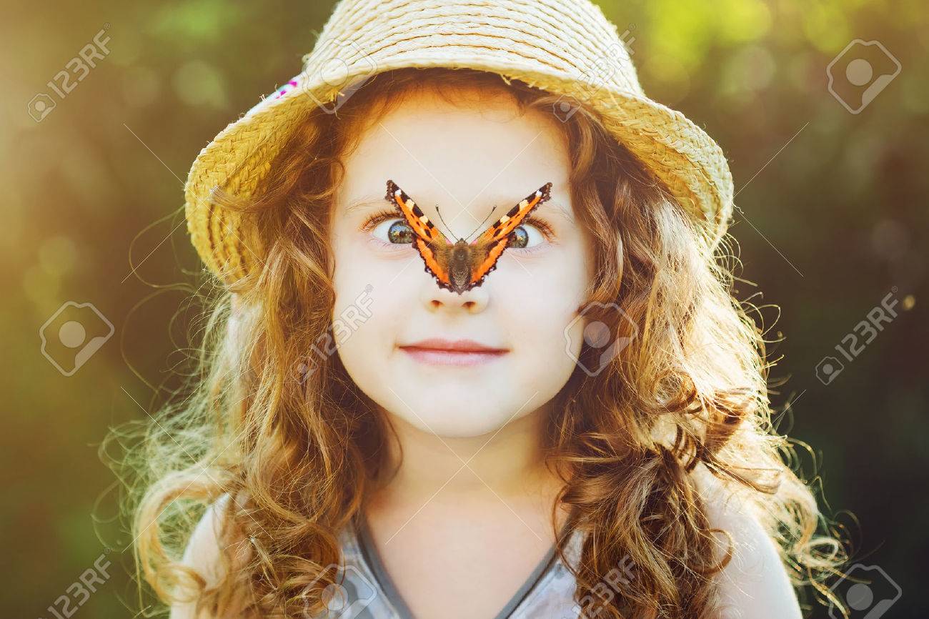 彼女の鼻の上の蝶に驚いた少女は少女の顔に焦点を当てます の写真素材 画像素材 Image