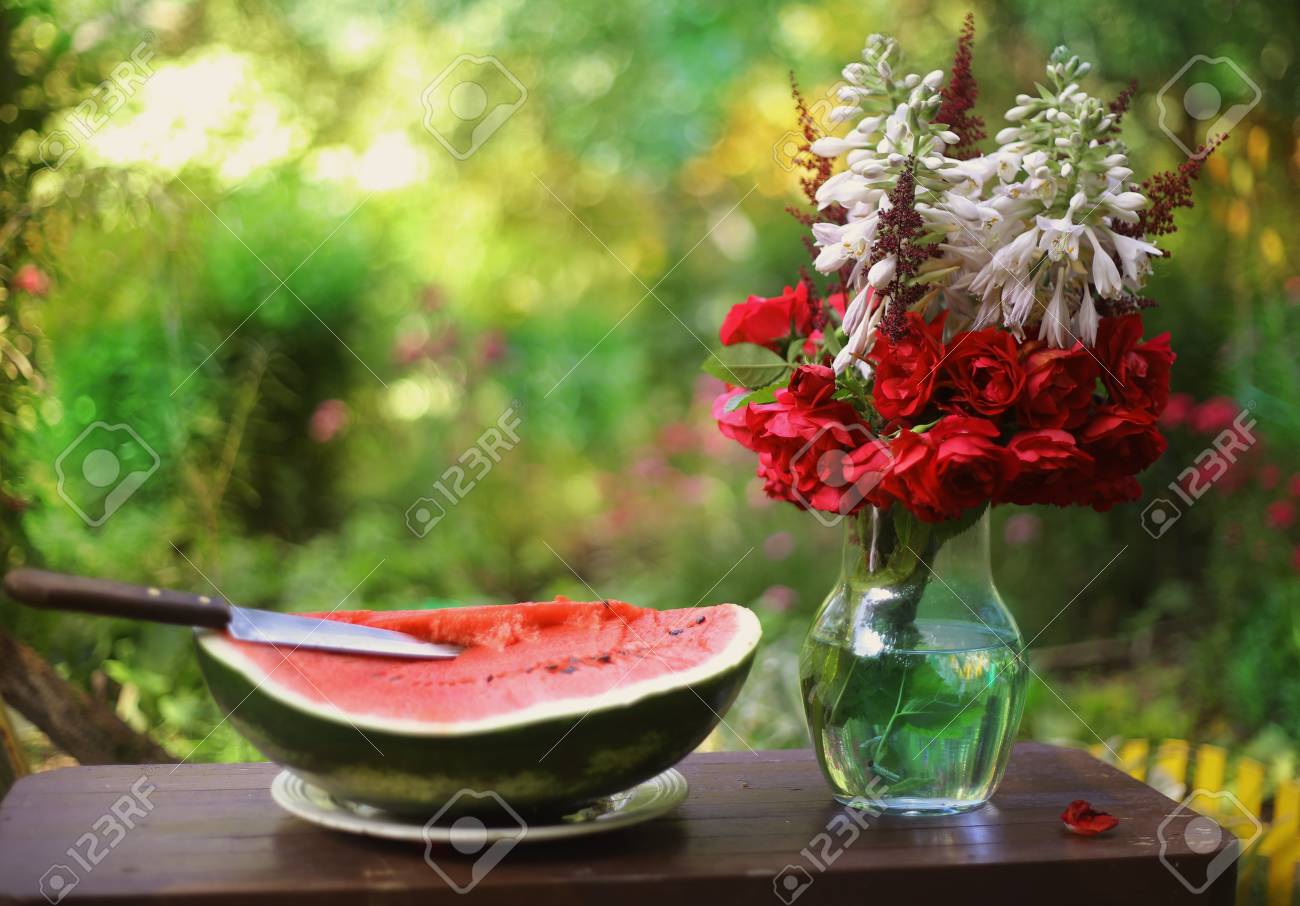 Water Melon Cut With Knife And Roses Flowers In Vase On Green