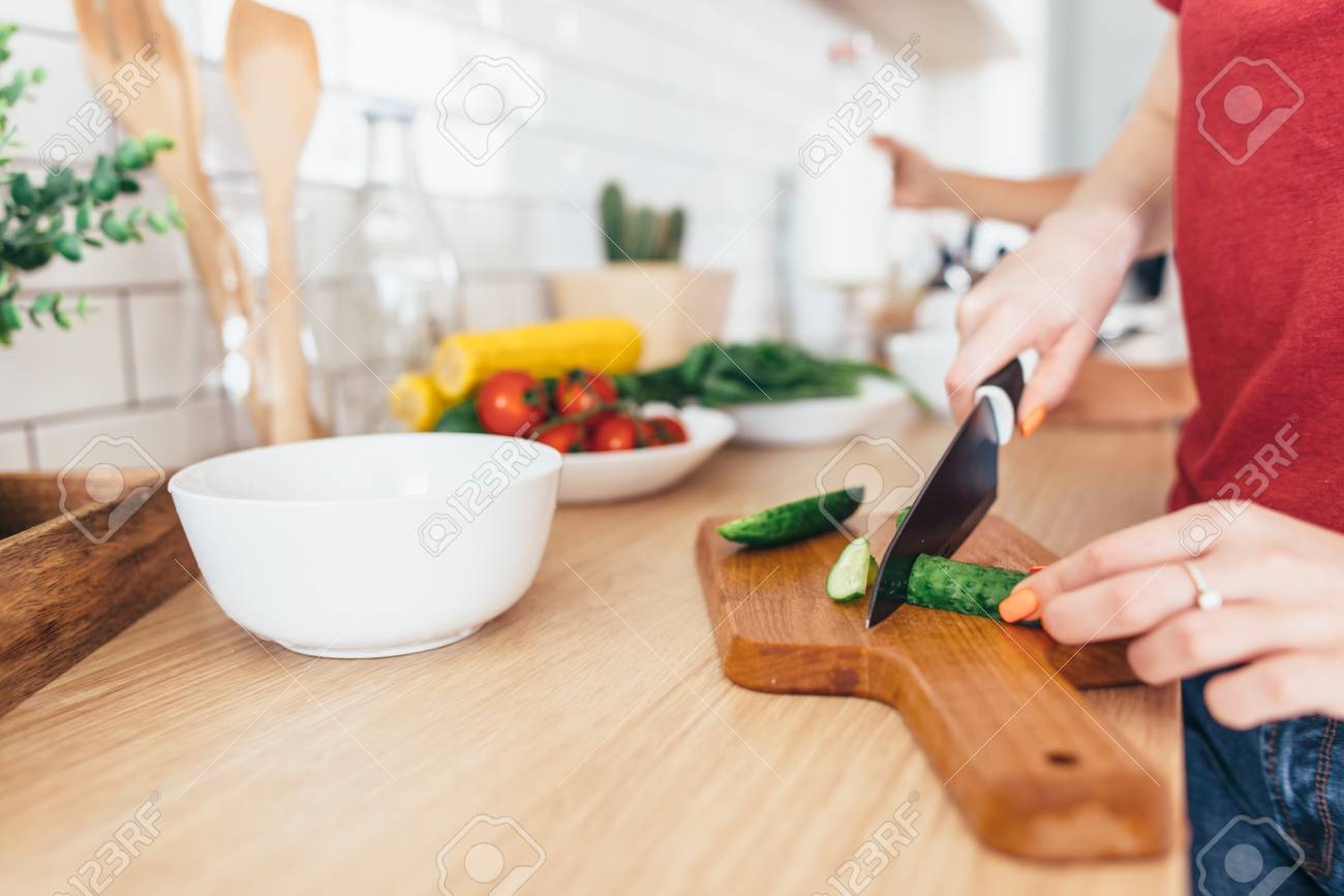 Woman cutting cucumber on the wooden board. - 93882793 Woman cutting cucumber on the wooden board. - 93882793