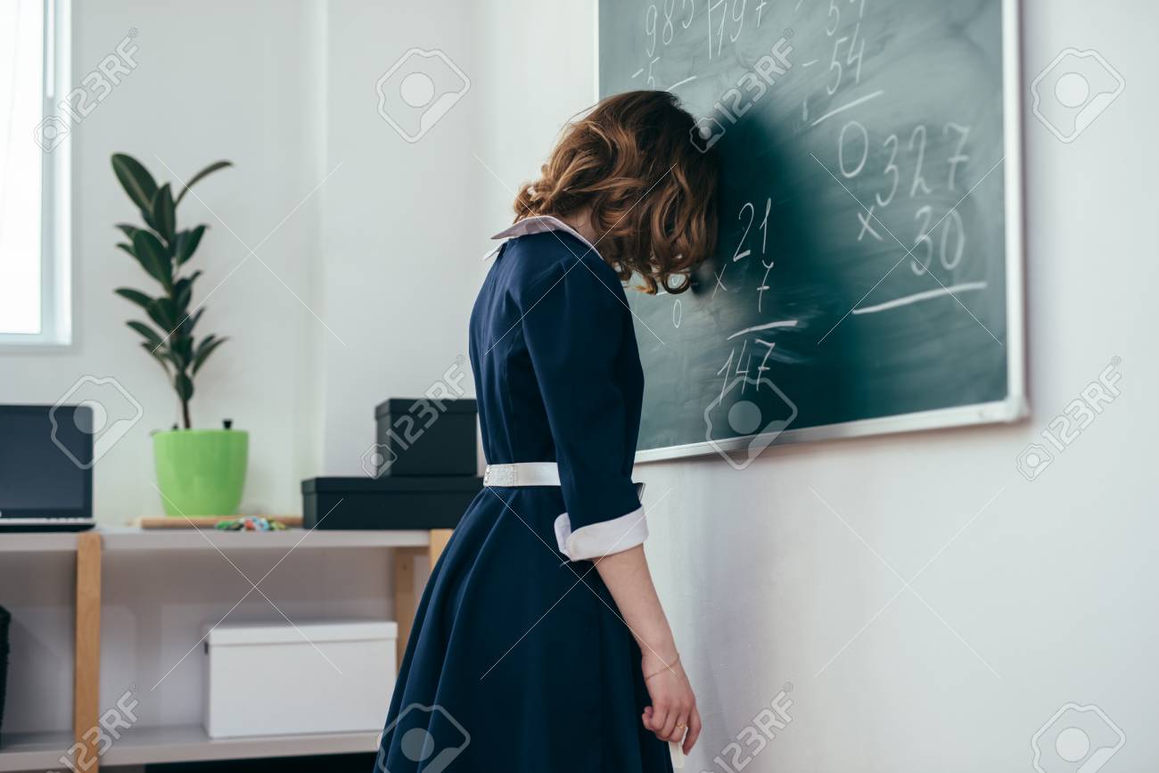 Sad schoolgirl standing in front of blackboard. - 104360654 Sad schoolgirl standing in front of blackboard. - 104360654