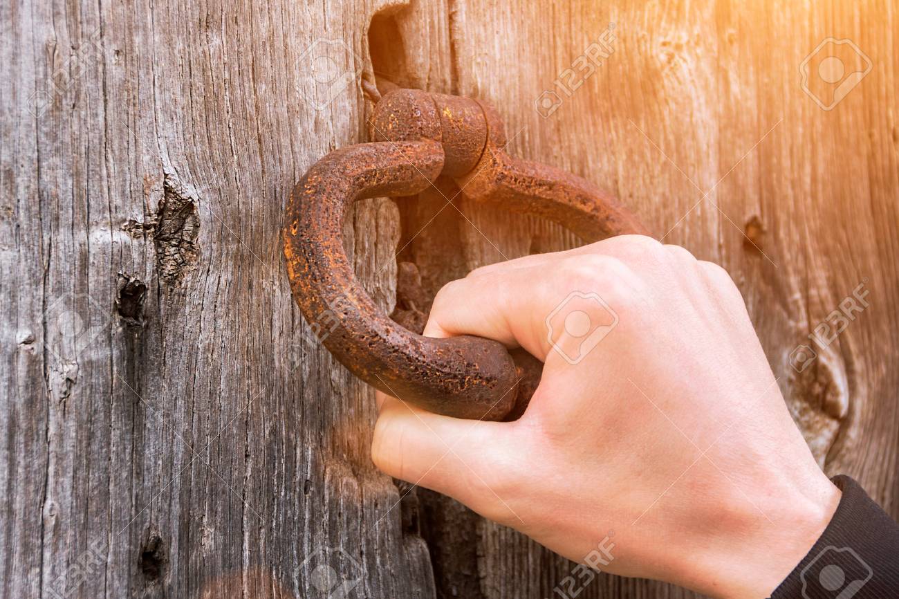 Old bell at the door, hand knocks on the wooden door - 101735416 Old bell at the door, hand knocks on the wooden door - 101735416