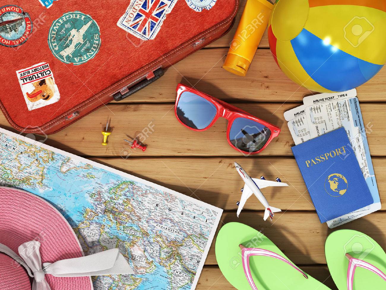 snglasses world map beach shoes sunscreen passport planeickets beach ball hat and old red suitcase for travel on the wood background