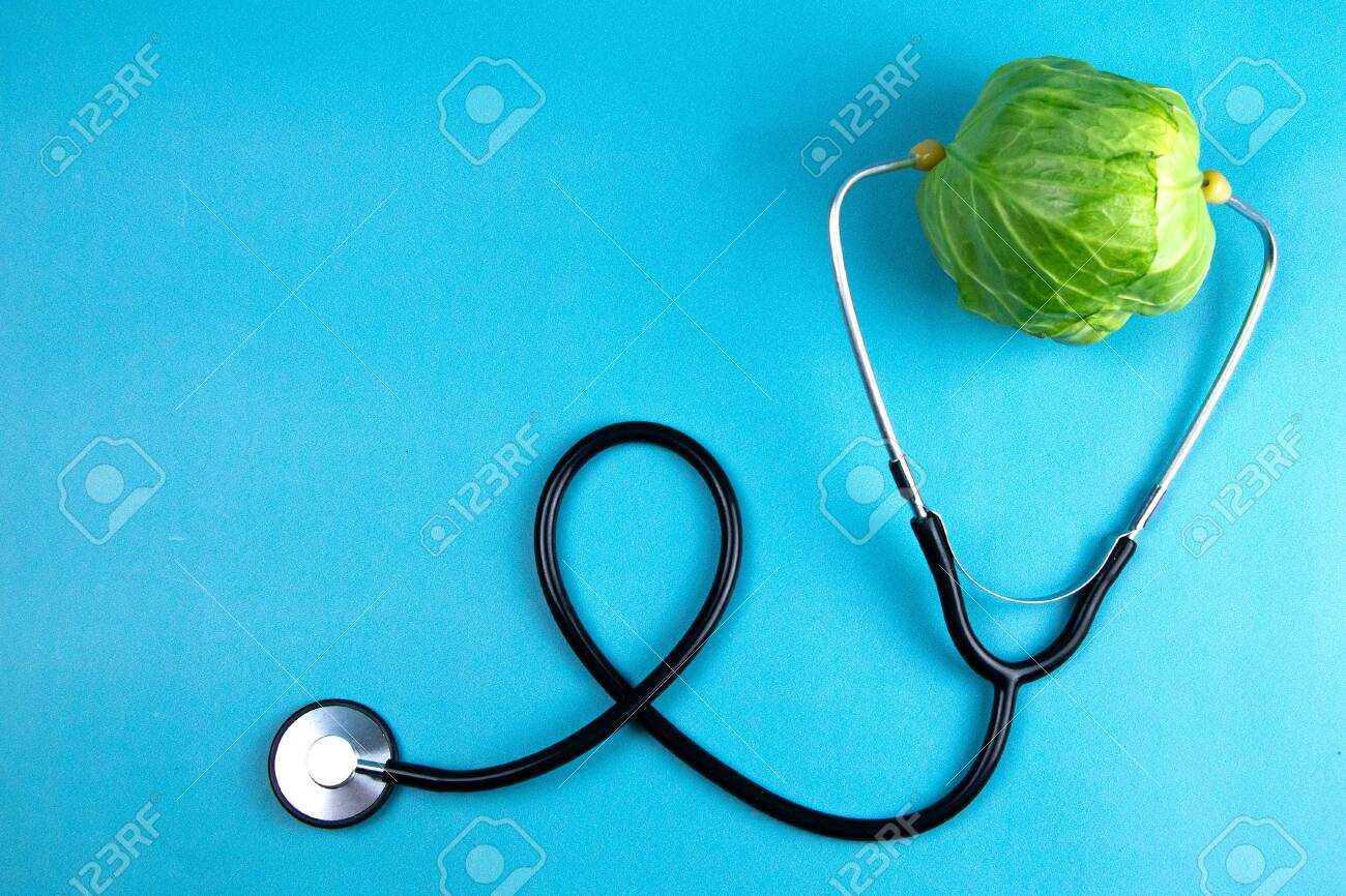Green young cabbage with a stethoscope isolated on blue background. Healthcare And Medicine. Top views with clear space - 140673241 Green young cabbage with a stethoscope isolated on blue background. Healthcare And Medicine. Top views with clear space - 140673241