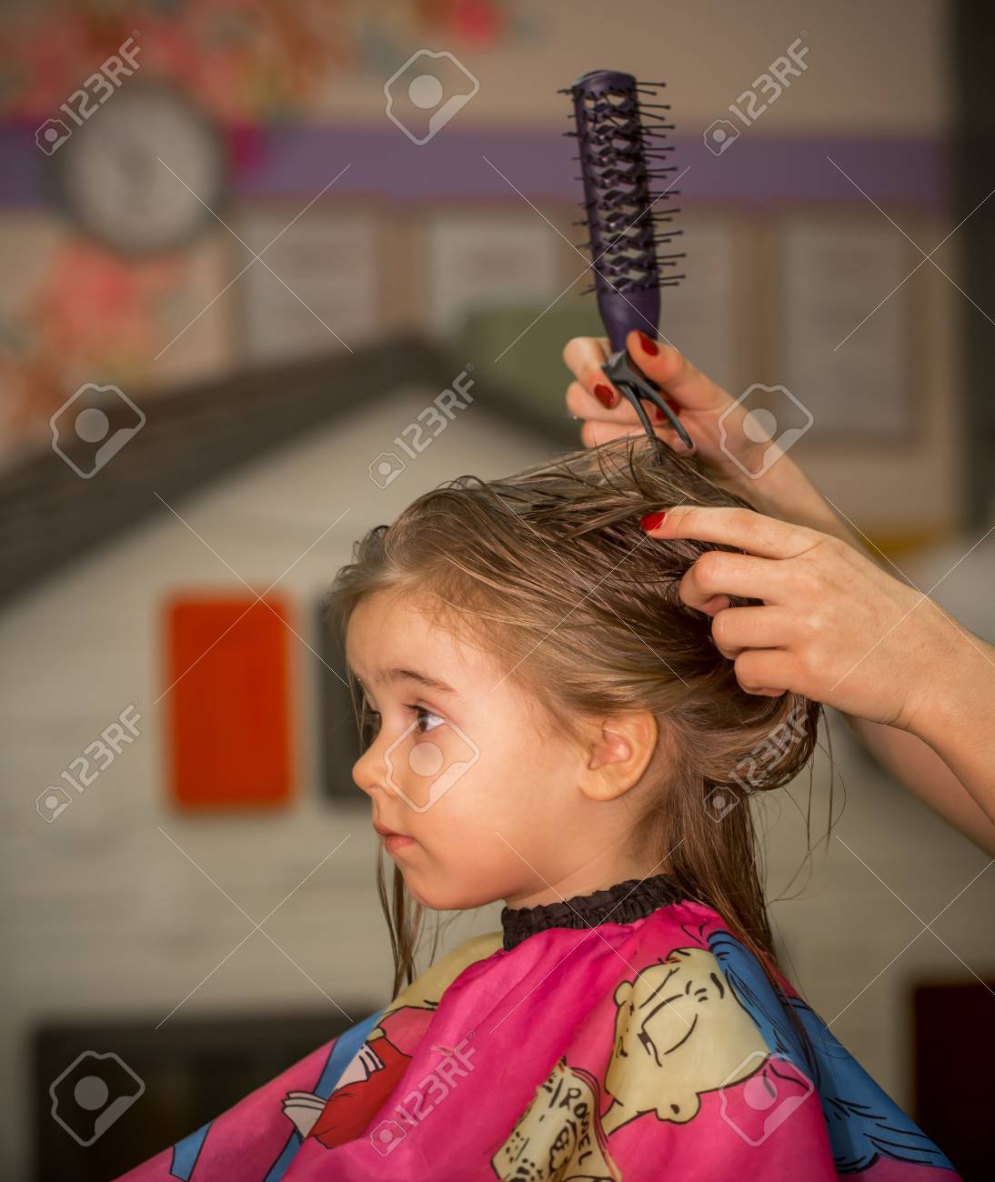 Beautiful Little Girl With Long Hair Cuts Hair In The Barbershop