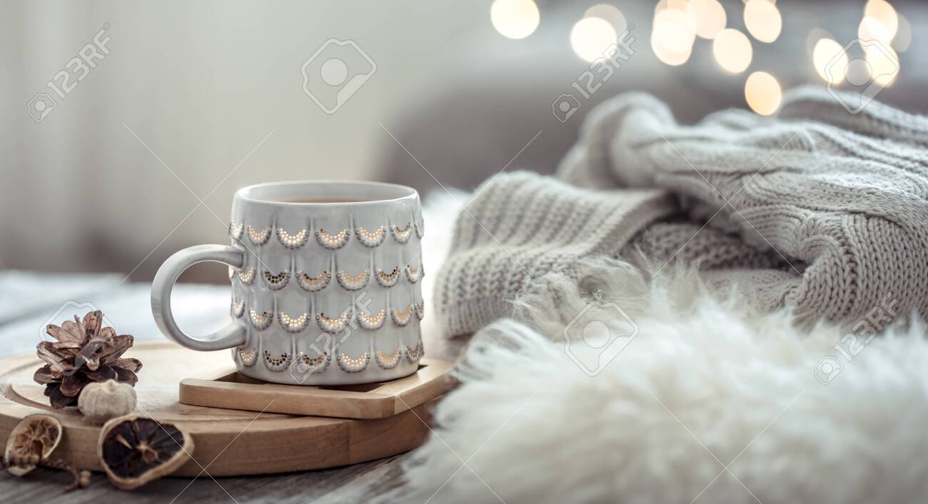 Coffee cup over Christmas lights bokeh in home on wooden table with sweater on a background and decorations. Winter mood, holiday decoration, magic Christmas. - 127901121 Coffee cup over Christmas lights bokeh in home on wooden table with sweater on a background and decorations. Winter mood, holiday decoration, magic Christmas. - 127901121