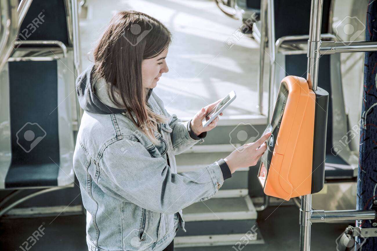A young woman contactless pays for public transport. Payment by card, Bank transfer . - 132708643 A young woman contactless pays for public transport. Payment by card, Bank transfer . - 132708643