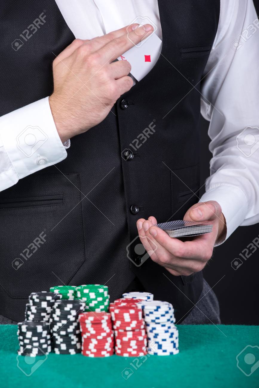 ディーラーのクローズ アップは テーブル上のチップを賭けてトランプを保持しています の写真素材 画像素材 Image