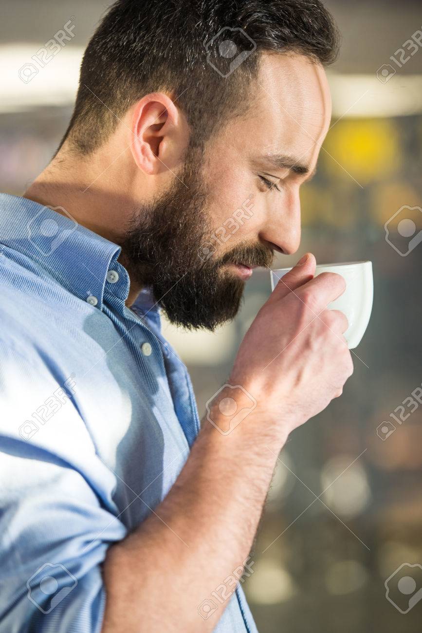 ガラス越しのコーヒーのカップを持つ男性の側面図です 彼はカメラを見てください の写真素材 画像素材 Image