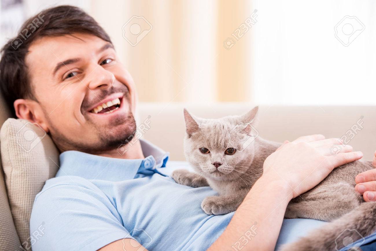 Sourire Jeune Homme Avec Son Chat Mignon Sur Le Canape A La Maison Banque D Images Et Photos Libres De Droits Image