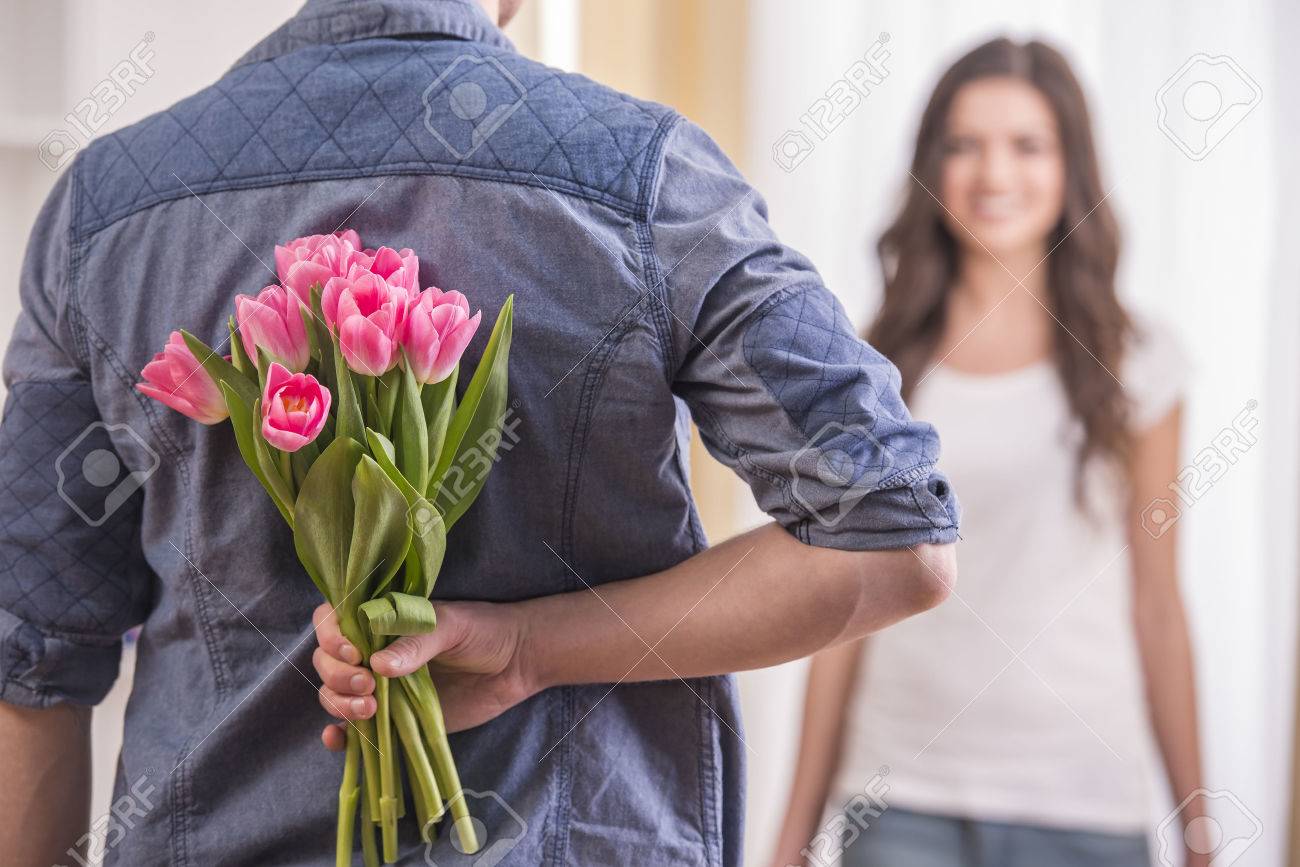 Der Junge Mann Versteckt Blumen Hinter Dem Rucken Um Seine Freundin Zu Hause Lizenzfreie Fotos Bilder Und Stock Fotografie Image