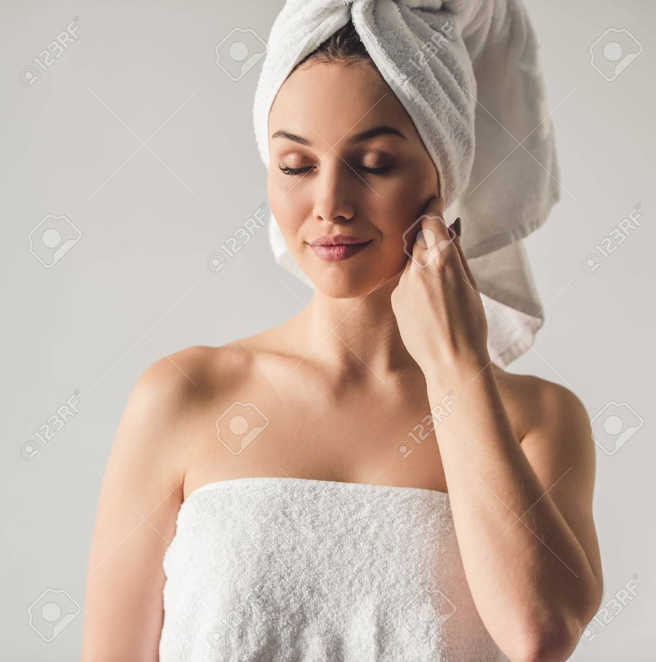 彼女の肌に触れると灰色の背景に 笑みを浮かべて彼女の頭の上にバスタオルを持つ魅力的な若い女の子の肖像画 の写真素材 画像素材 Image 7381