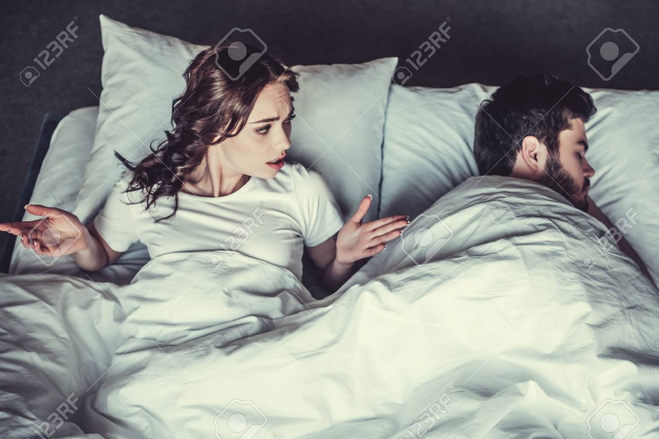 不満の若い女の子と彼氏がベッドで寝ています の写真素材 画像素材 Image