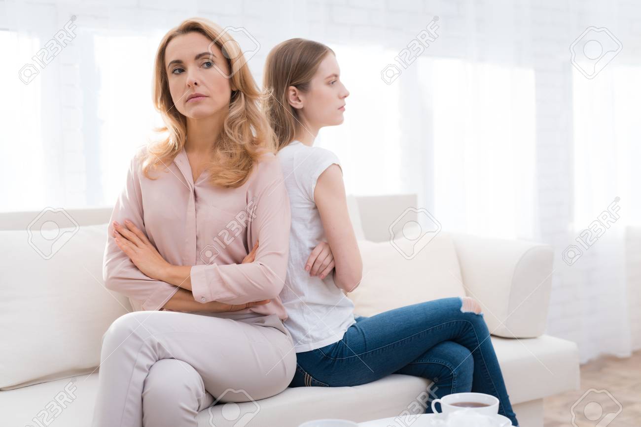A woman and a girl are sitting on the sofa back to back. - 91595294 A woman and a girl are sitting on the sofa back to back. - 91595294