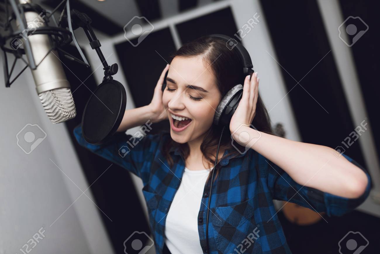 The girl sings her song in a modern recording studio. She sings the song very emotionally. In front of her is a studio microphone. - 96915452 The girl sings her song in a modern recording studio. She sings the song very emotionally. In front of her is a studio microphone. - 96915452
