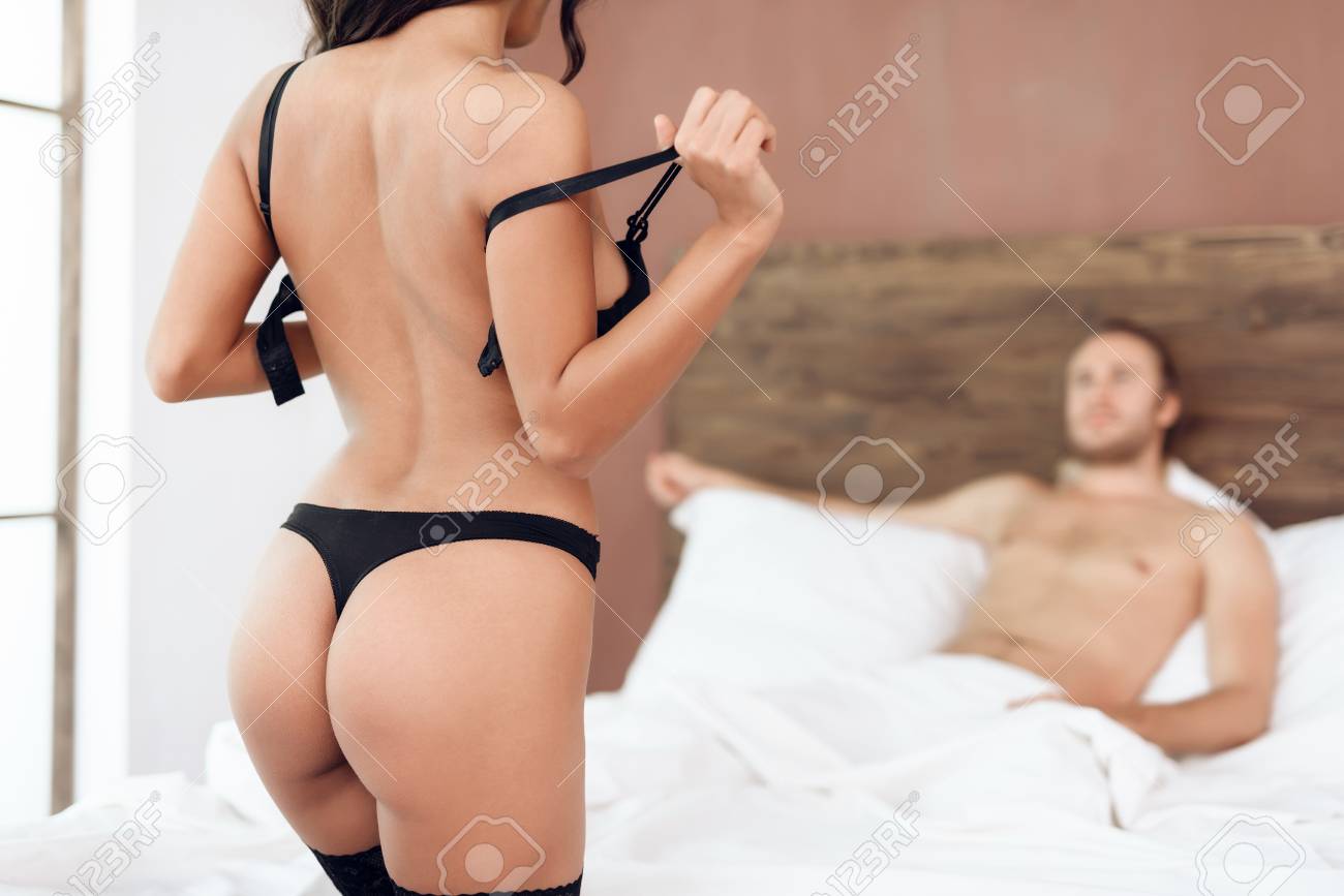 セックスフレンド ランジェリー姿 ランジェリー姿の情熱的な女性がベッドに横たわっている男の前でブラを脱ぐ。性的関係。親密な親密さ。ストリップショーの写真素材・画像素材 Image 99617012