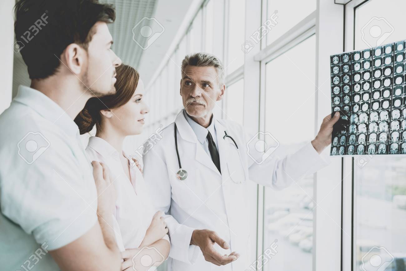 Tense Male Doctor Indicates on Image of Roentgen. Showing Patients Results at Diagnostic Centre. Rapid Improvement. Doctors and Patients Discuss in Clinic. Professional in Coat with Stethoscopes. - 104541558 Tense Male Doctor Indicates on Image of Roentgen. Showing Patients Results at Diagnostic Centre. Rapid Improvement. Doctors and Patients Discuss in Clinic. Professional in Coat with Stethoscopes. - 104541558