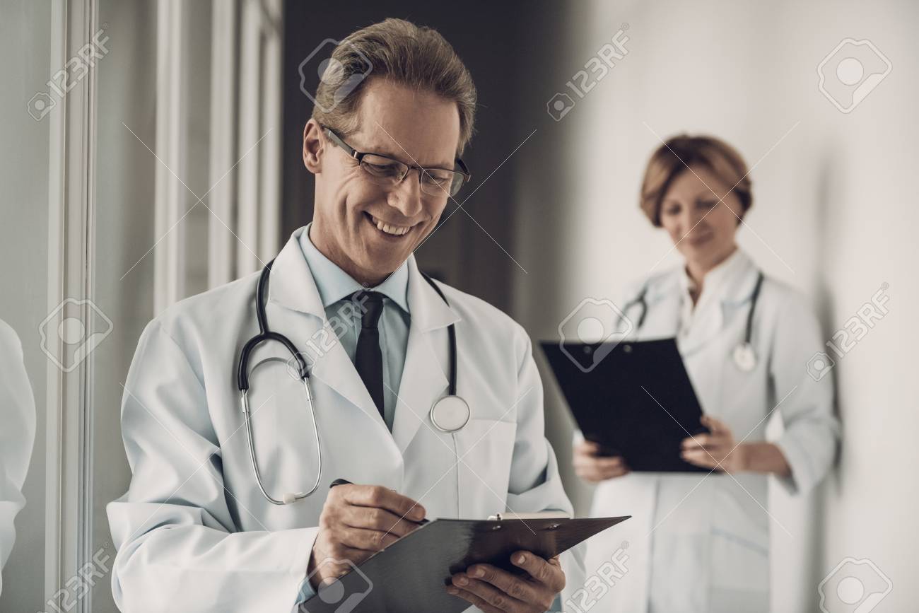 Doctor and Nurse Filling up Medical History. Portrait of Caucasian Experienced Medicine Attractive Workers in Uniform Making Diagnosis Standing in Hospital. Healthcare Concept - 107349459 Doctor and Nurse Filling up Medical History. Portrait of Caucasian Experienced Medicine Attractive Workers in Uniform Making Diagnosis Standing in Hospital. Healthcare Concept - 107349459