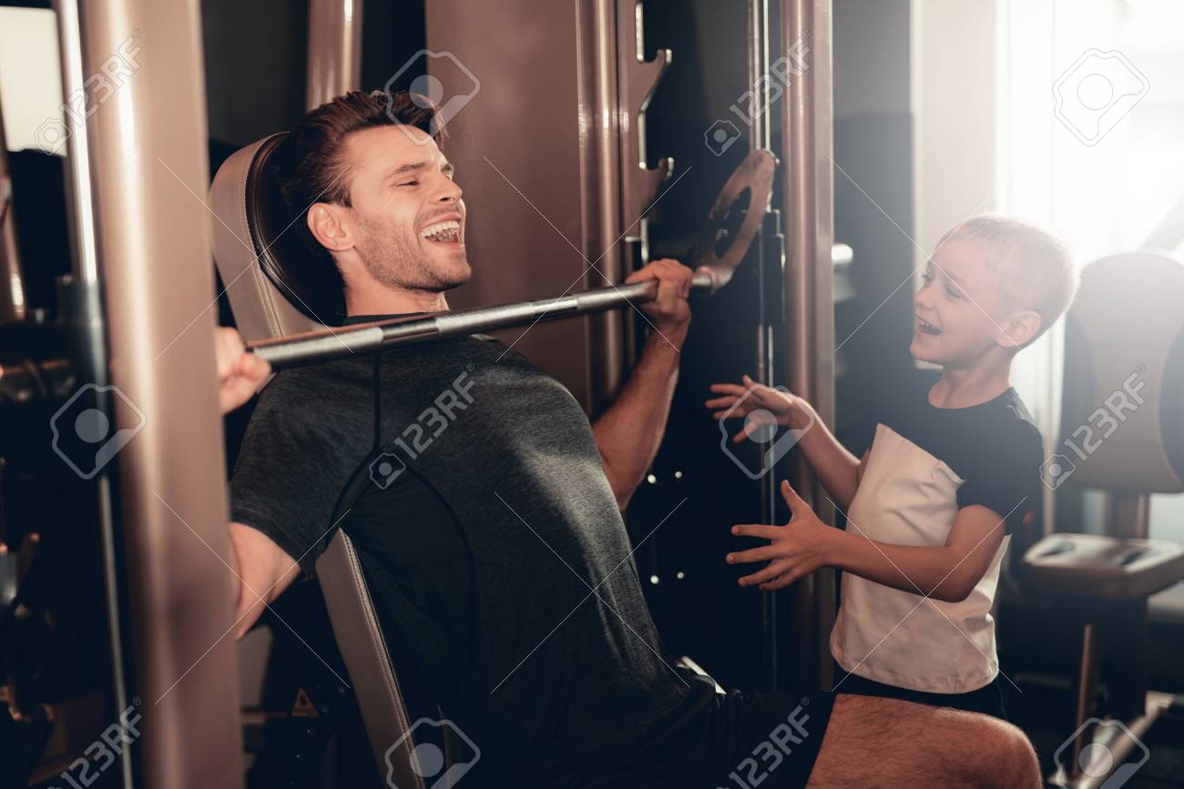 Son Support To Father While Lifting The Barbell. Parenthood Relationship. Sporty Family Concept. Active Lifestyle. Happy Childhood. Holiday Leisure. Working Out Together. Fitness Day. - 109559343 Son Support To Father While Lifting The Barbell. Parenthood Relationship. Sporty Family Concept. Active Lifestyle. Happy Childhood. Holiday Leisure. Working Out Together. Fitness Day. - 109559343