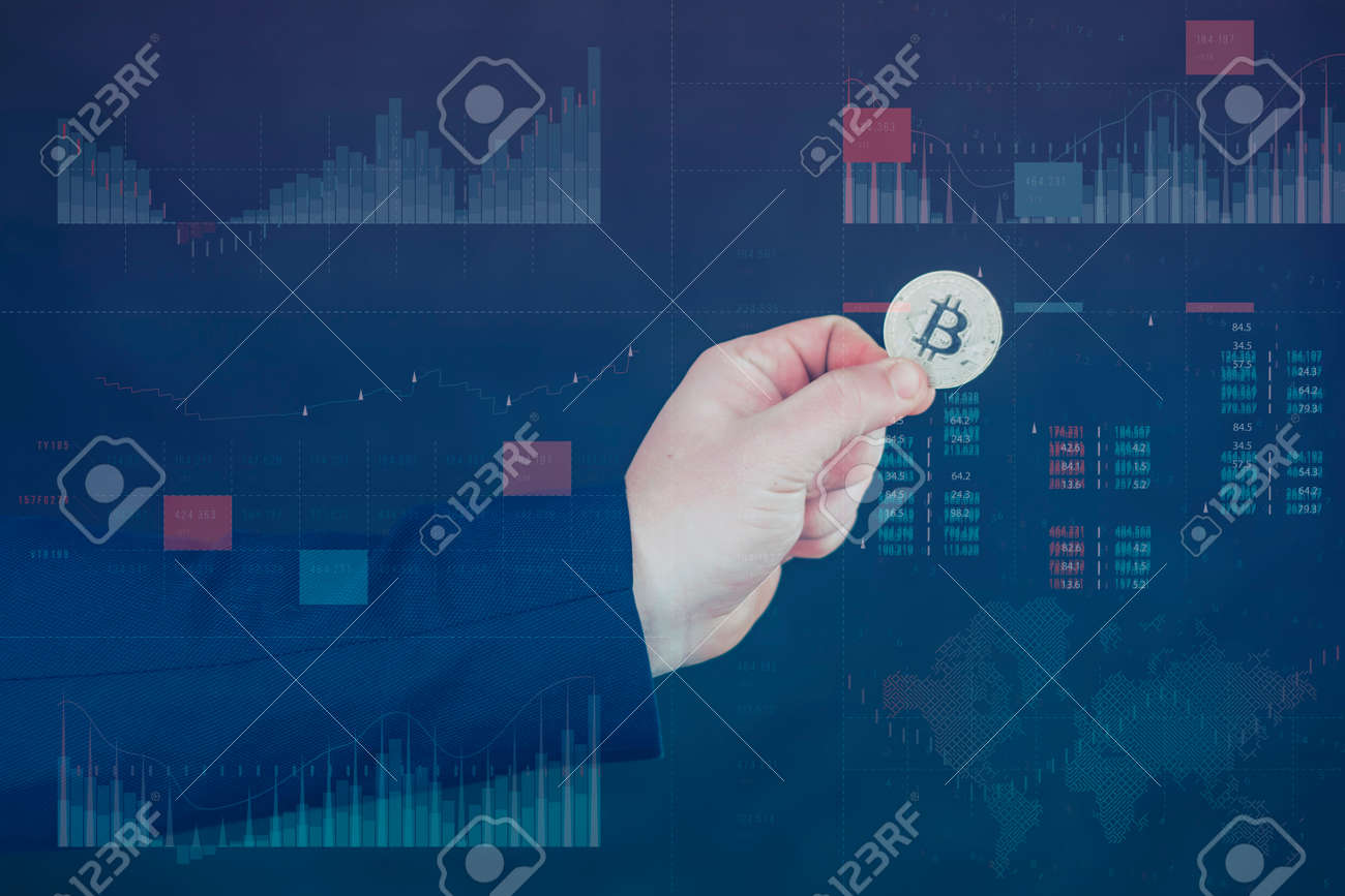 사업가는 정보 홀로그램 패널에 금 비트코인 동전을 들고 있으며, 통계를 통해 암호화폐 가상 화폐와 블록체인 개념의 하락과 성장을  보여줍니다. 로열티 무료 사진, 그림, 이미지 그리고 스톡포토그래피. Image 167062132