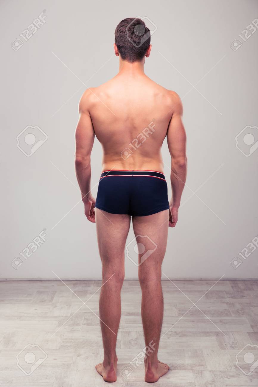 back view portrait of a muscular man standing in studio stock photo