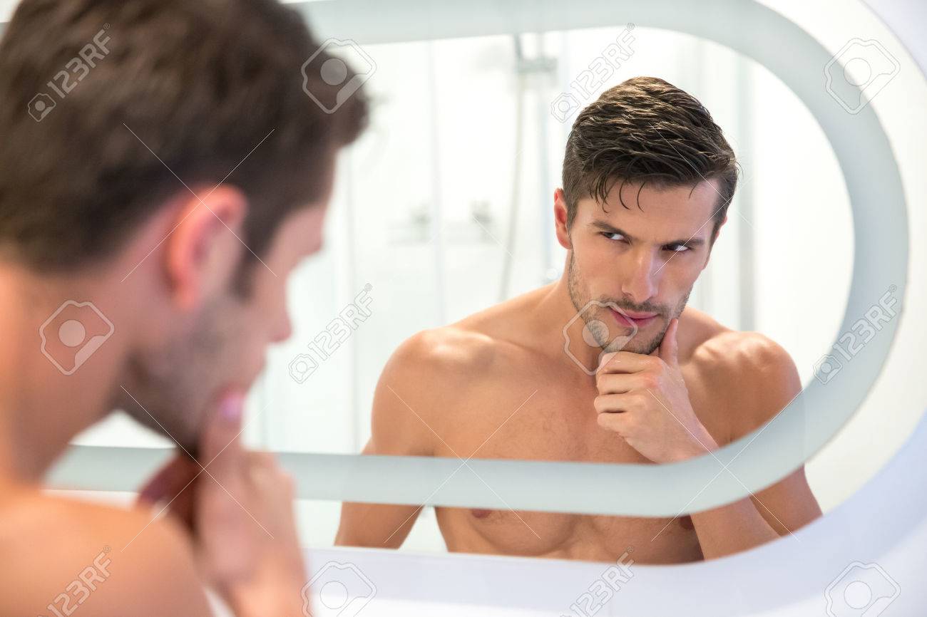 Portrait Of A Handsome Man Looking At His Reflection In The Mirror In  Bathroom Stock Photo, Picture and Royalty Free Image. Image 45863195., image size:1300x866