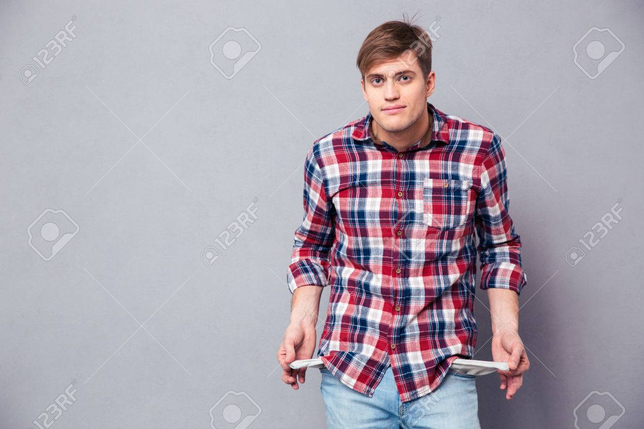 Poor handsome young man in checkered shirt and jeans showing empty pockets over grey background - 50383603 Poor handsome young man in checkered shirt and jeans showing empty pockets over grey background - 50383603