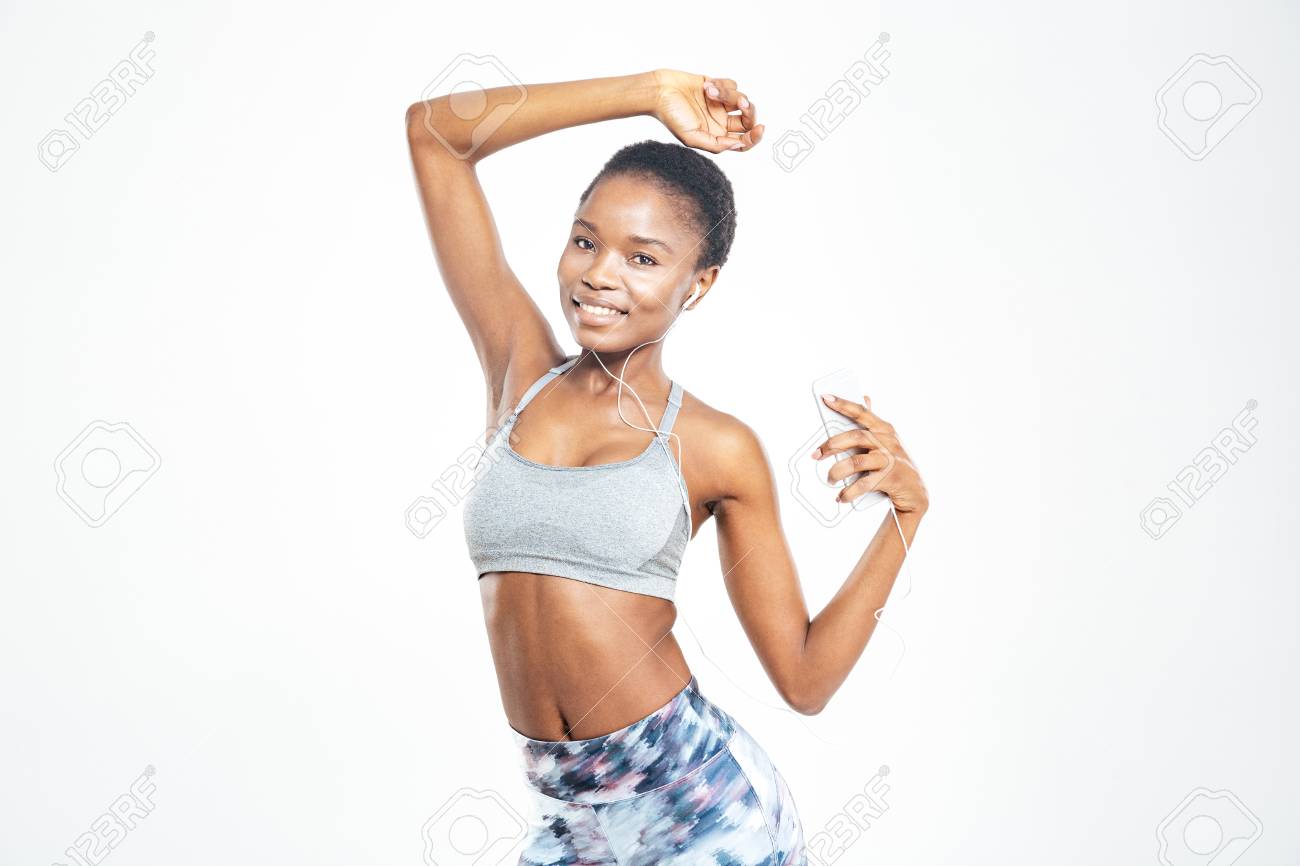 幸せな若いアフリカ系アメリカ人スポーツ選手のポーズを魅力的で白い背景にスマート フォンから音楽を聴いて の写真素材 画像素材 Image