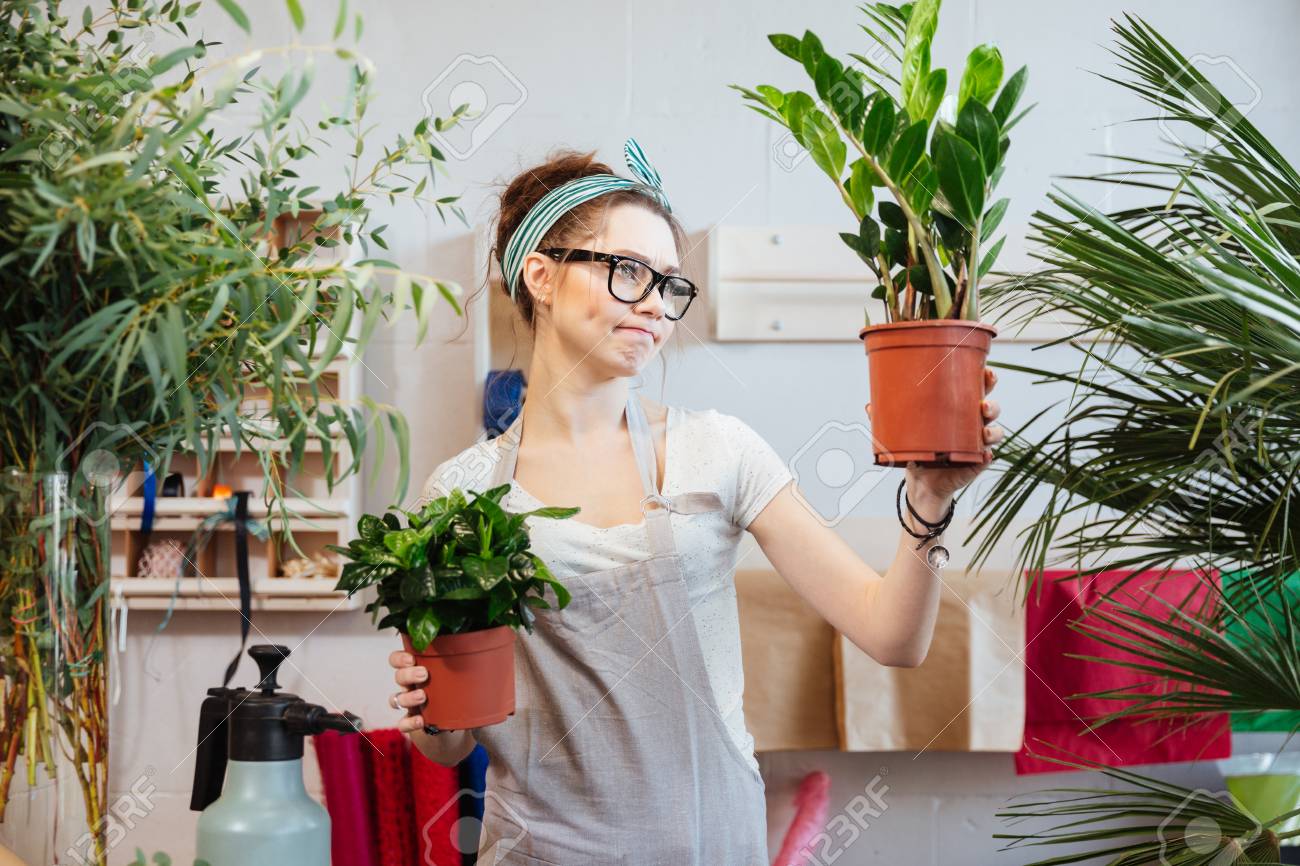 植物の植木鉢や思考を保持しているメガネで物思いにふけるかわいい若い女性花屋 の写真素材 画像素材 Image