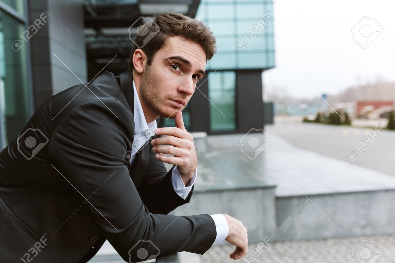 オフィスの近くの屋外で立ってスーツで物思いにふけるビジネスマン 横から見た図 の写真素材 画像素材 Image