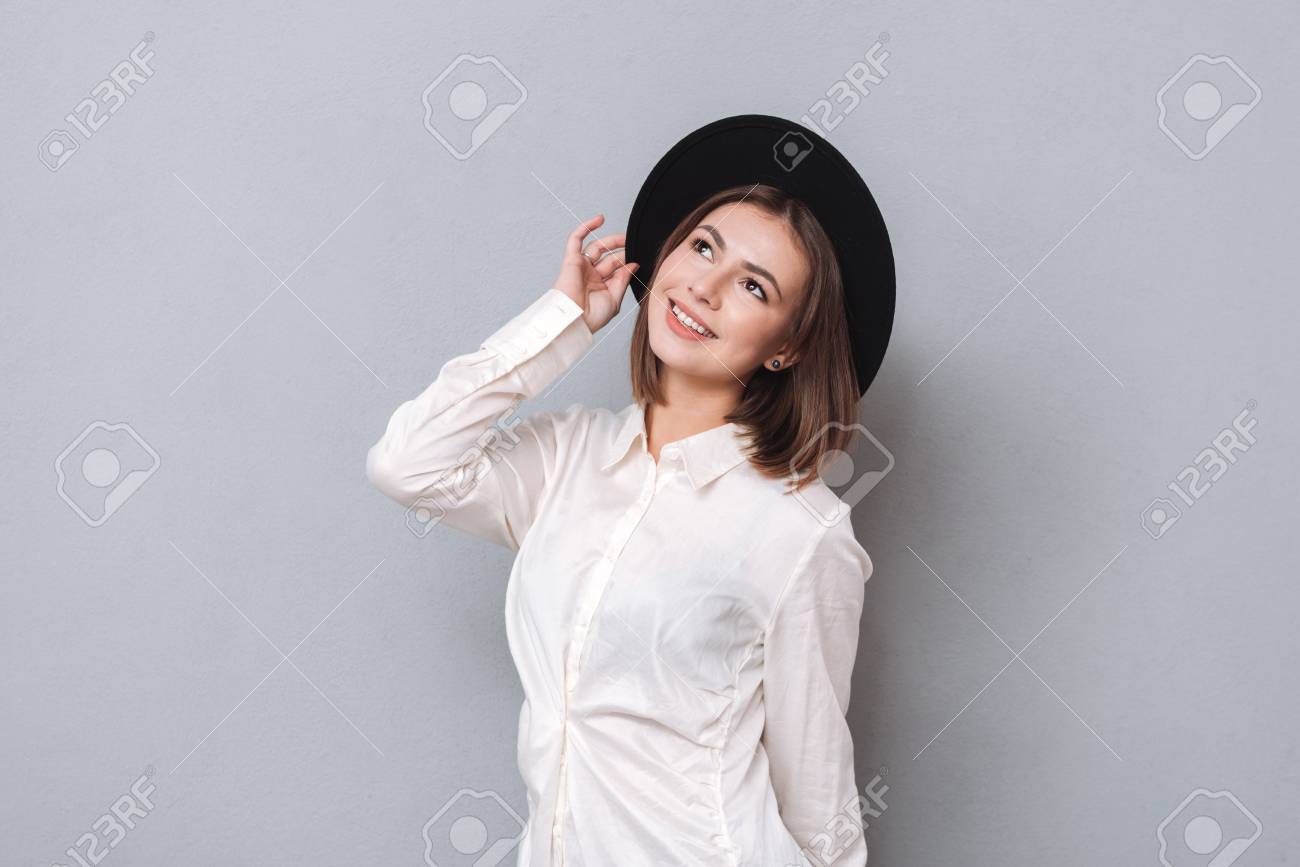 帽子でポーズをとって 白い背景の上見上げて笑顔若い女性の肖像画 の写真素材 画像素材 Image