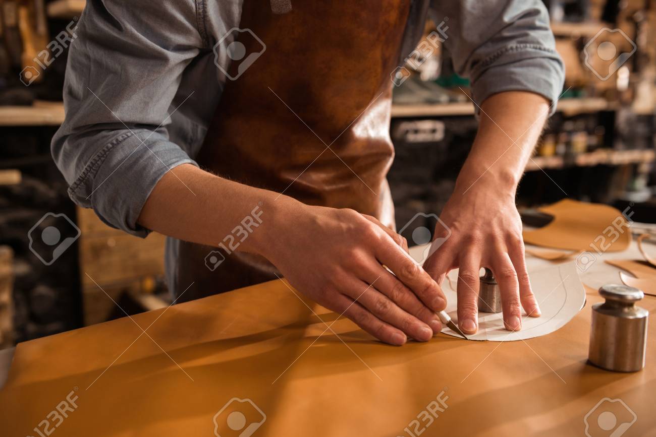 Close up of a shoemaker cutting leather in a workshop - 82350485 Close up of a shoemaker cutting leather in a workshop - 82350485