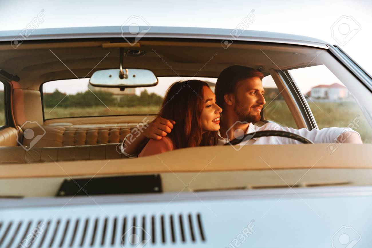 若いカップルが車の中に一緒に座っているとよそ見しながらハグを笑っています フロント ウィンドウの表示 の写真素材 画像素材 Image 84178707