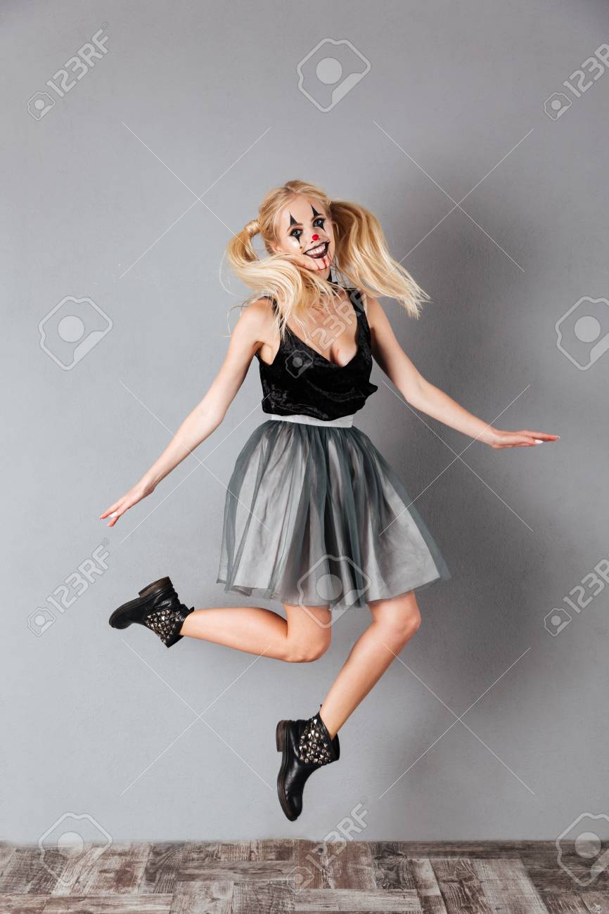 ハロウィン ピエロ メイクアップと血の縞ジャンプと灰色の背景に分離カメラ目線で陽気な金髪の女の完全な長さの肖像画 の写真素材 画像素材 Image 1406
