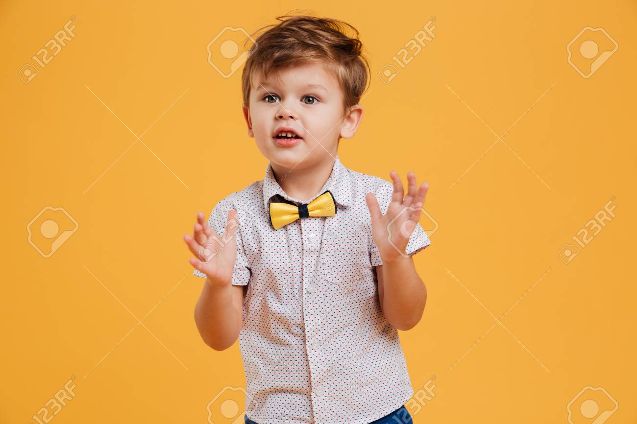 黄色の背景の上に孤立した興奮した小さな男の子の子供の画像 脇を見て の写真素材 画像素材 Image