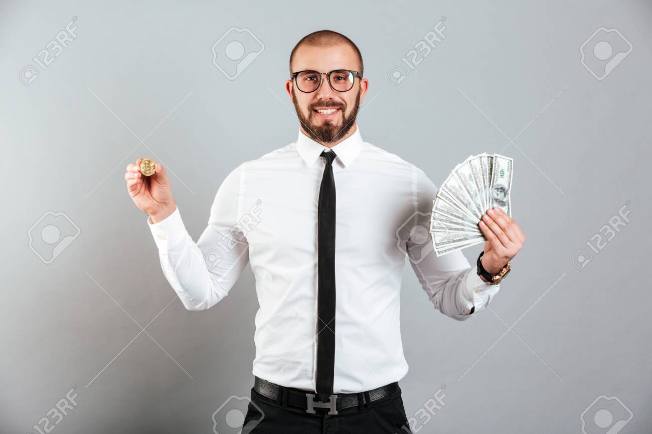 Foto De Homem Rico 30s Em Óculos E Terno Mostrando Bitcoin E Muito Dinheiro  Moeda De Dólar Isolado Sobre Fundo Cinza Foto Royalty Free, Gravuras,  Imagens e Banco de fotografias. Image 97777403