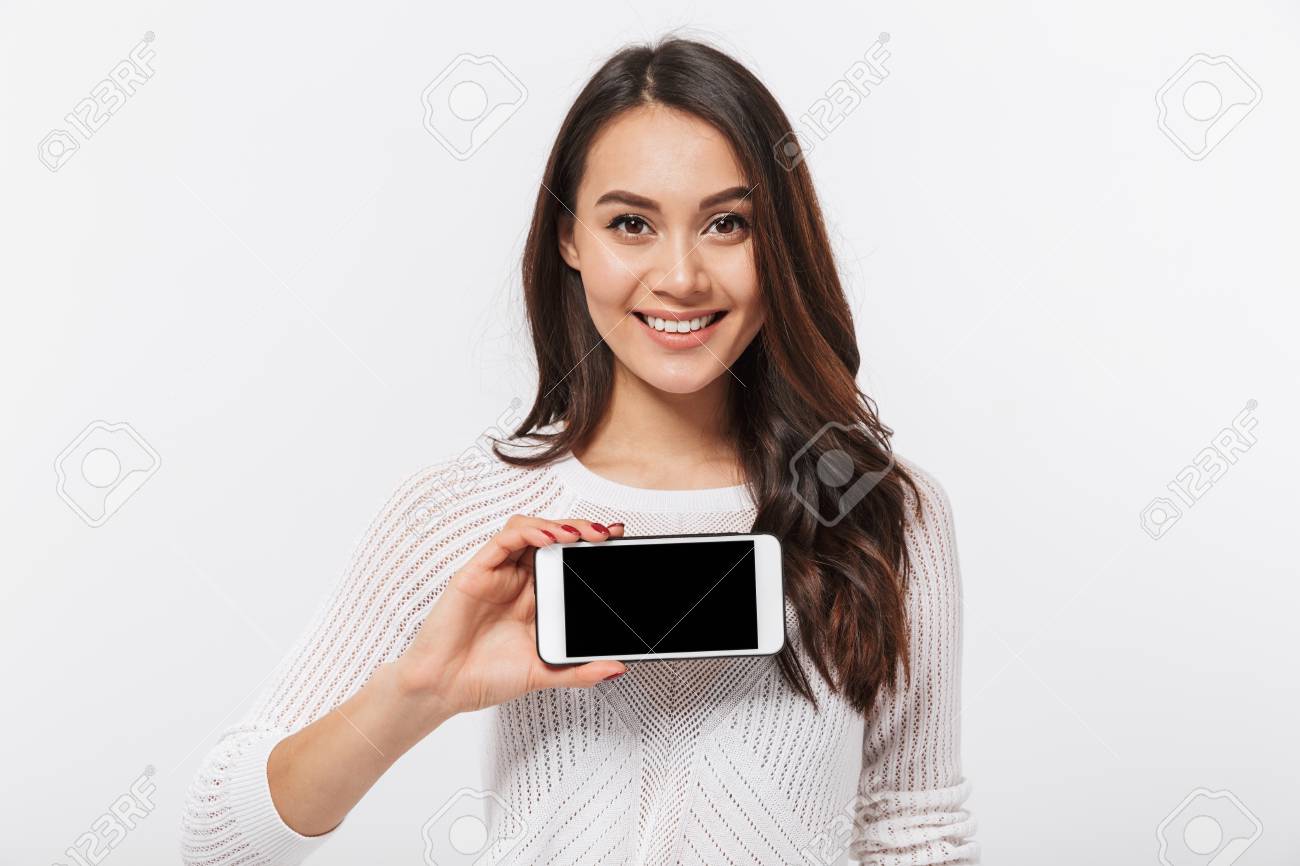 Portrait of a smiling asian businesswoman showing blank screen mobile phone isolated over white background - 101488377 Portrait of a smiling asian businesswoman showing blank screen mobile phone isolated over white background - 101488377