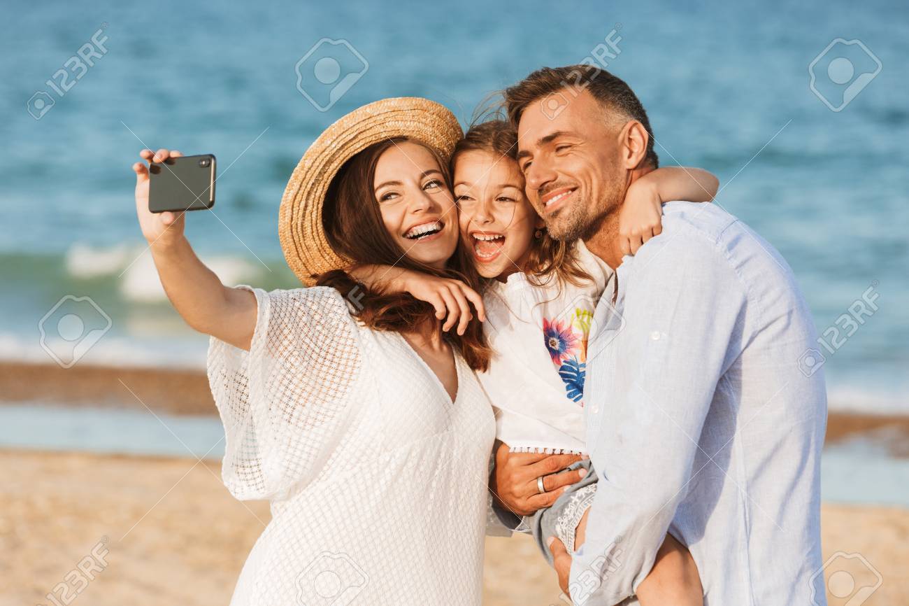 Happy family spending good time at the beach together, taking selfie - 107579466 Happy family spending good time at the beach together, taking selfie - 107579466