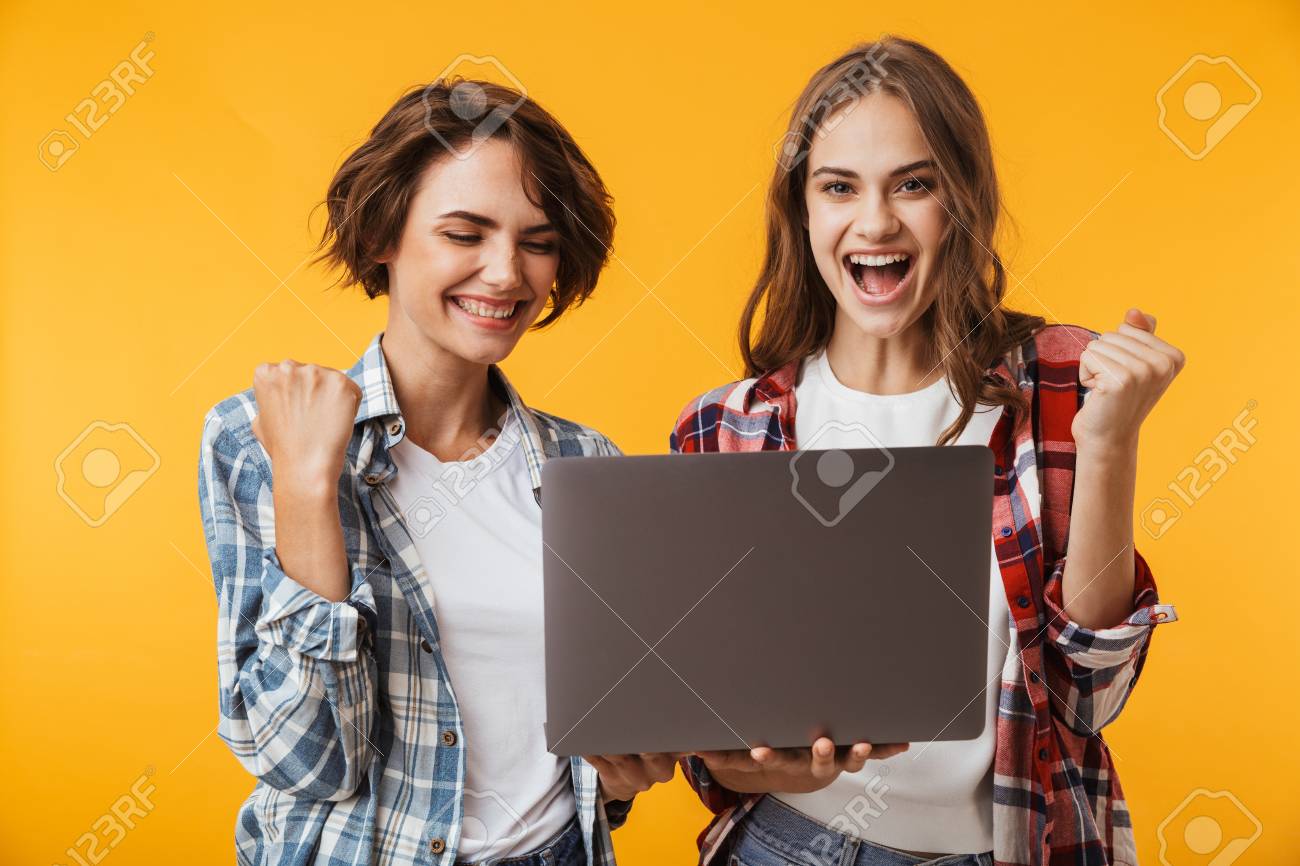 Image of amazing women friends isolated over yellow wall background using laptop computer make winner gesture. - 110707507 Image of amazing women friends isolated over yellow wall background using laptop computer make winner gesture. - 110707507
