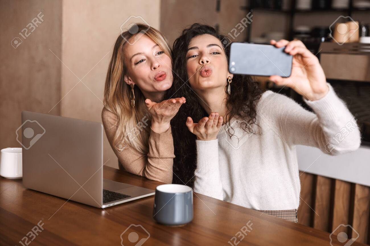 Image Of Excited Happy Girls Friends Sitting In Cafe Using Laptop Computer Take A Selfie By Phone Stock Photo Picture And Royalty Free Image Image 123854857