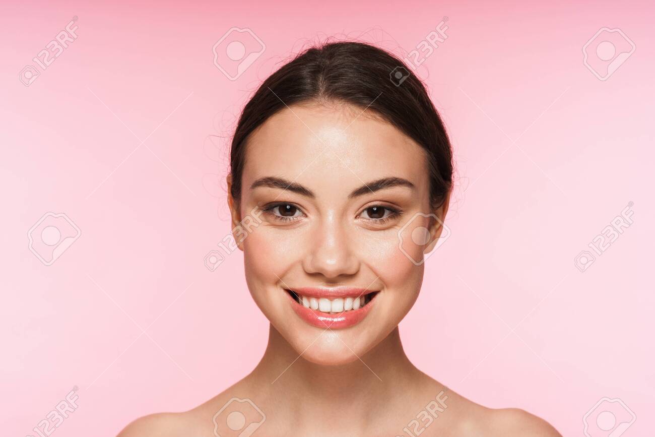 Beauty portrait of a beautiful smiling young brunette woman standing isolated over pink background - 139087799 Beauty portrait of a beautiful smiling young brunette woman standing isolated over pink background - 139087799